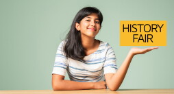 Indian asian teenage girl pointing at blank while sitting across table against green background