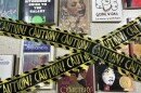 Photos of books with yellow and black caution tape over them.