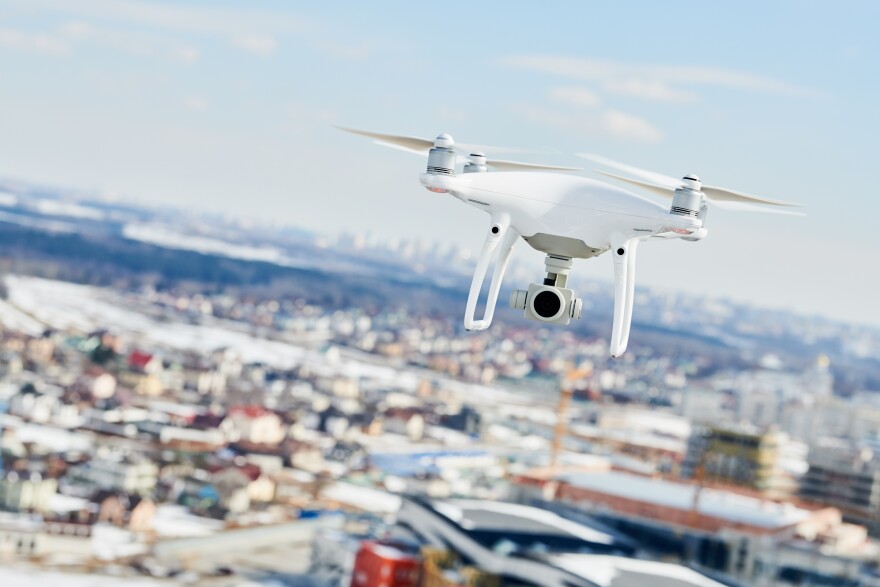 A drone quadcopter with a digital camera hovers over the city.