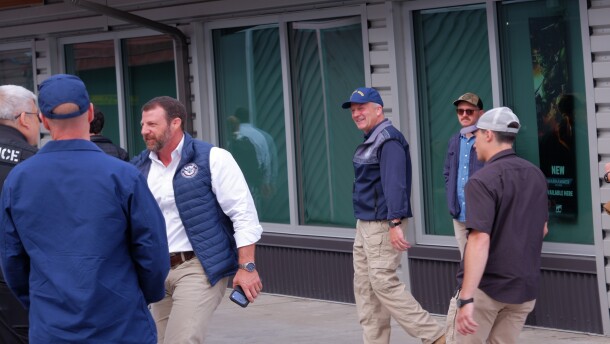 Secretary of Homeland Security Markwayne Mullin shakes hands with a police officer outside of the Kodiak Marketplace on August 11 as Sen. Dan Sullivan walks beside him.