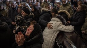Relatives and friends attend a funeral ceremony for four of the Ukrainian military servicemen, who were killed during an airstrike in a military base in Yarokiv, in a church in Lviv, Ukraine, Tuesday, March 15, 2022. At least 35 people were killed and many wounded in Sunday's Russian missile strike on a military training base near Ukraine's western border with NATO member Poland. (AP Photo/Bernat Armangue)