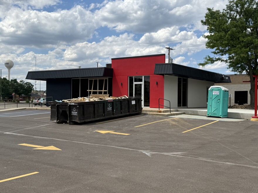 A red and black building with a dumpster outside in an empty parking lot