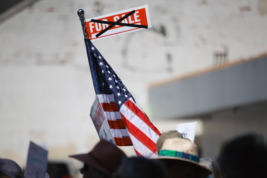 A for sale sign is crossed out while attached to an American flag during the annual May Day march on Thursday, May 1, 2025, in Seattle’s Capitol Hill neighborhood.