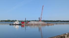 Contractors are using a floating crane to put tons of rocks in places to repair Bird Island Pier in a U.S. Army Corps of Engineers-led project.