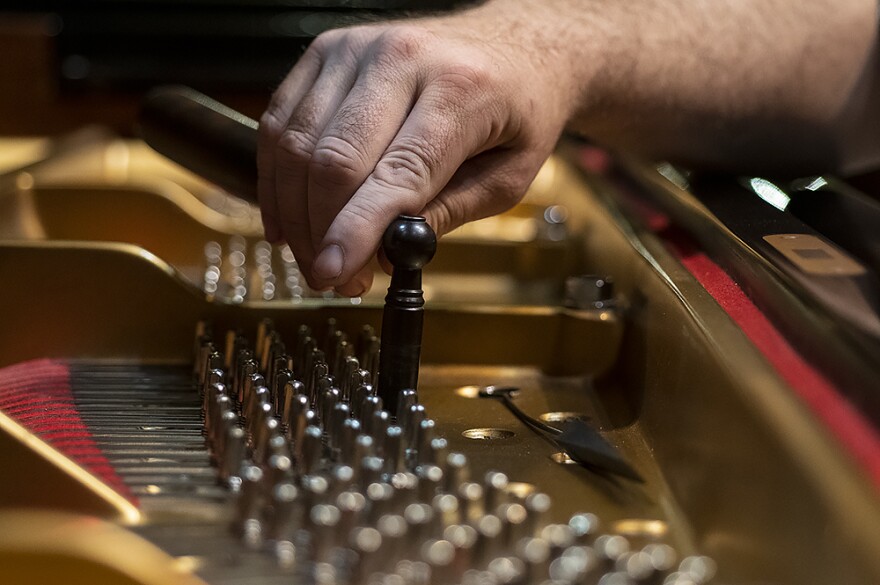 Preparing one of the Folly Theater’s grand pianos for a concert, Hulme makes an adjustment with his father’s tuning lever.&#13;