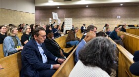 Utility Commissioner Donald van der Vaart interrupted the hearing to ask audience members to lower their anti–data center signs.