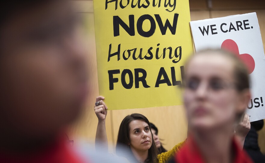 Protesters hold signs during the public hearing on Wednesday, November 1, 2017, at City Hall in Seattle. 