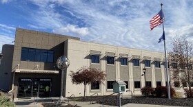 Exterior of a large office building with an American flag on a pole in front of it.