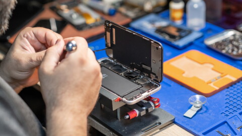 A skilled technician performs phone repair and replaces a battery.