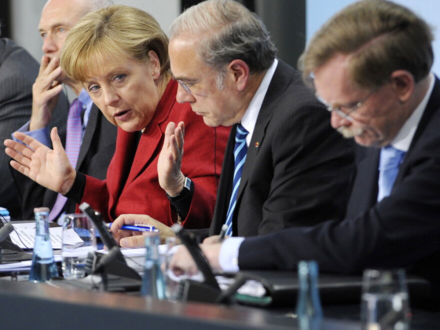 German Chancellor Angela Merkel (left) addresses a press conference Wednesday in an effort to calm investors about the looming European debt crisis. She said the emergency funds to Greece need to be accelerated.