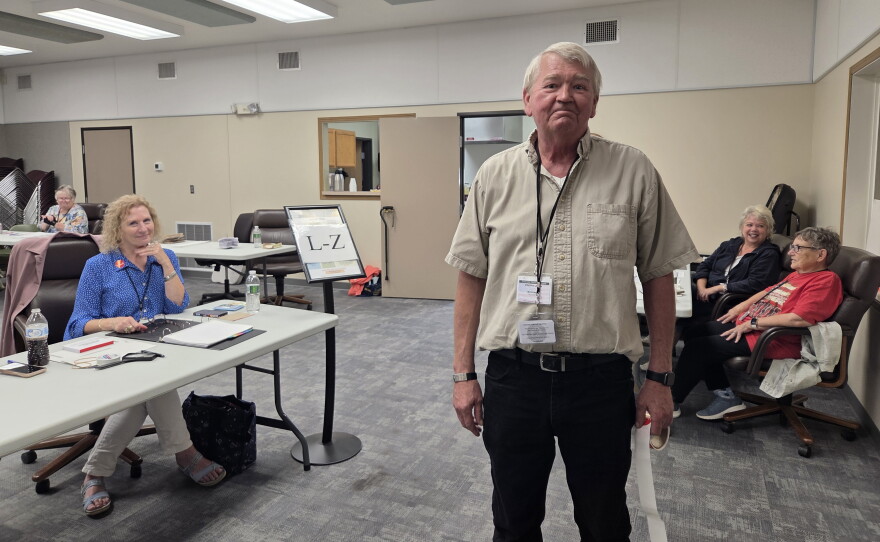 Bagley election judge Mark Edevold stops to smile for a photo with a roll of "I Voted" stickers in his hand