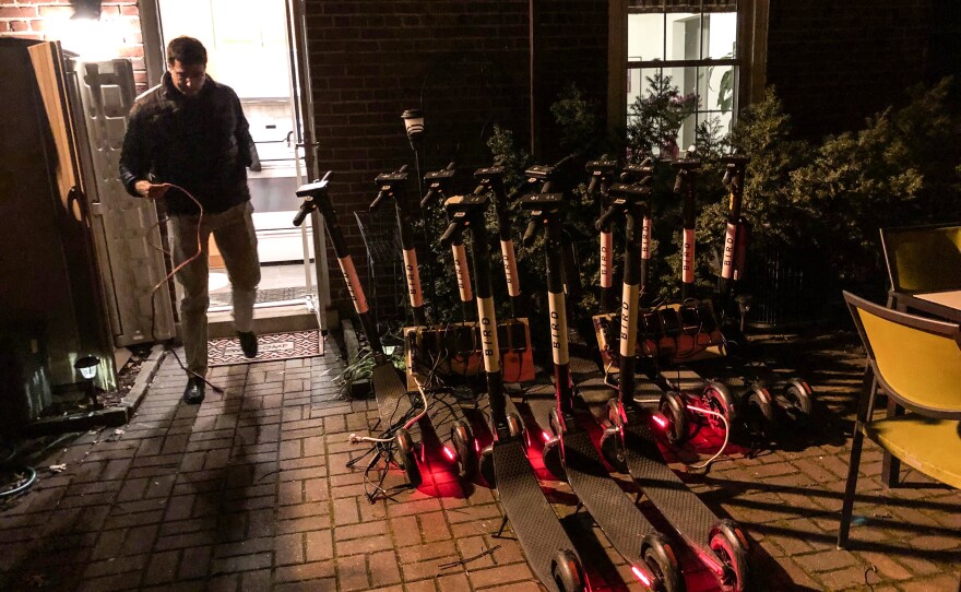Joel Kirzner charges Bird scooters on his patio in Arlington, Va., on March 4. He routinely picks up scooters after his workday is finished and charges them overnight for the companies Bird and Lime.