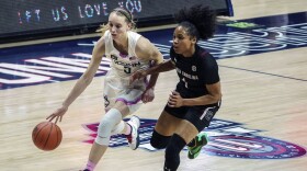 Connecticut guard Paige Bueckers (5) drives the ball against South Carolina guard Zia Cooke (1) in the first half of an NCAA college basketball game in Storrs, Conn., Monday, Feb. 8, 2021. Connecticut lawmakers have been asked to update last year's state law that allows student athletes to be compensated for their name and likeness in marketing deals and enable them to use their state college or university's logo, mascot or other institutional marks when they're pitching products like sports drinks and apparel.