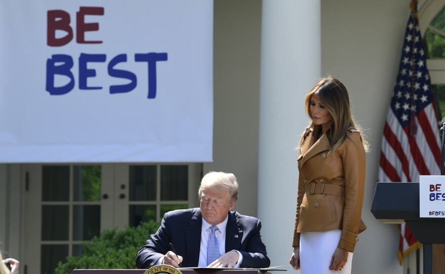President Donald Trump signs a proclamation as first lady Melania Trump watches during an event where the first lady announced her initiatives in the Rose Garden of the White House Monday.
