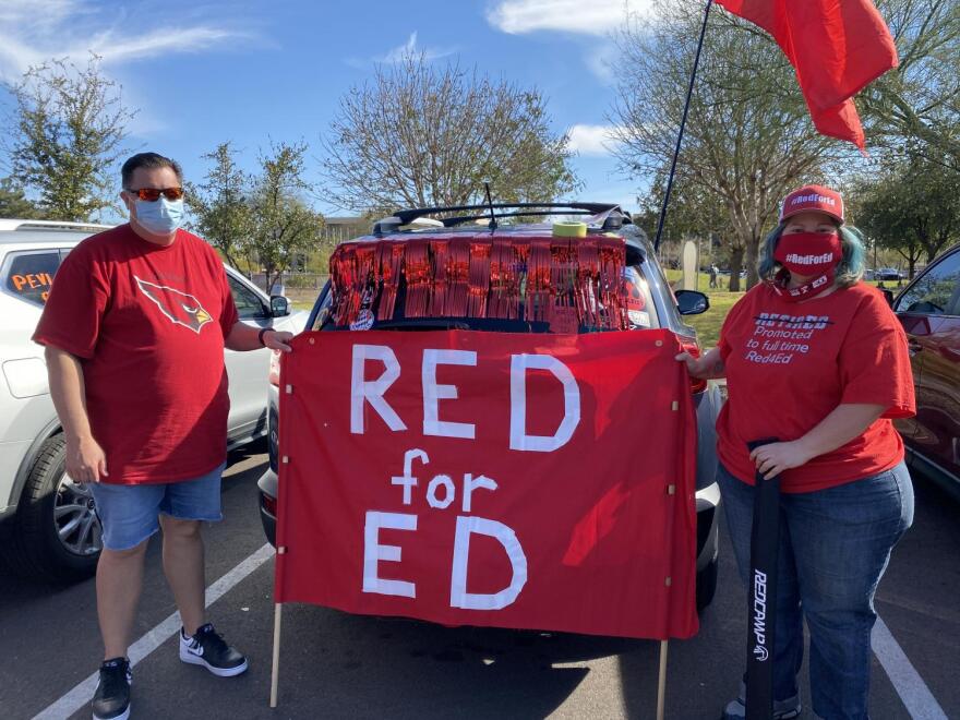 People hold up a sign that reads Red for Ed