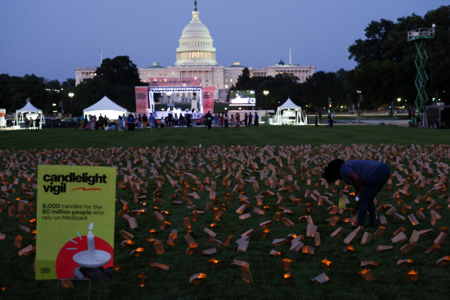 A demonstrator stands among battery powered candles in paper bags during a vigil in protest against potential cuts to Medicaid in Washington, D.C. on July 23, 2025.