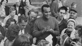 Harry Belafonte, alongside Ed Sullivan, signs autographs for fans outside CBS Studio 50 in New York City, circa 1955.