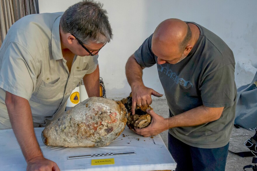 Project co-directors Brendan Foley and Theotokis Theodoulou inspect the torpedo-shaped lead cylinder recovered from the Antikythera shipwreck.
