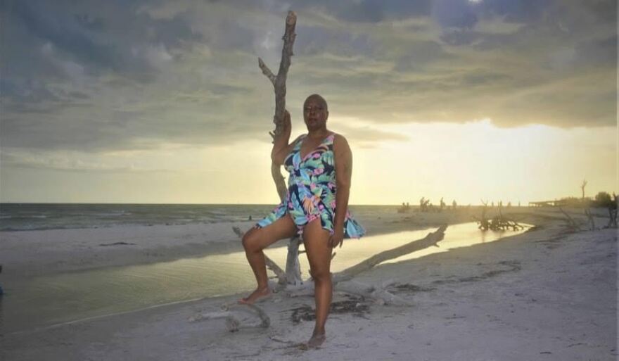 Sonja Brookins standing on a beach with the sun setting behind her. 