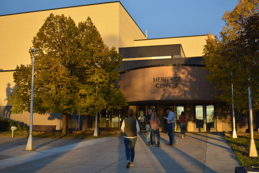 People stand outside of the entrance to a large building.