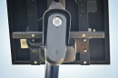 Outdoor, close-up photo of a small black camera attached to a small solar panel.