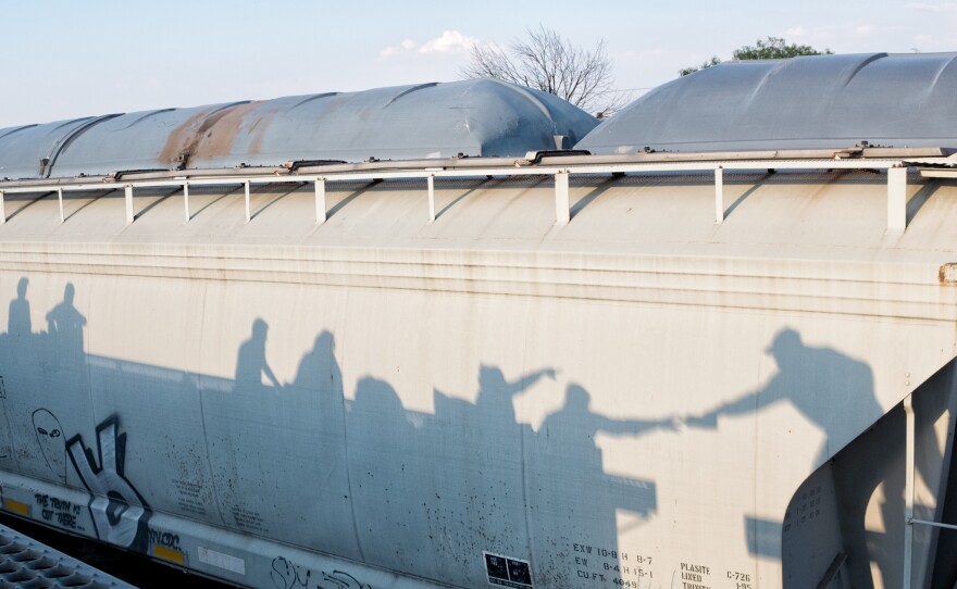 Men bring back snacks from a nearby convenience store for the women and children while the train is stopped, near Guanajuato, Oct. 22, 2017.