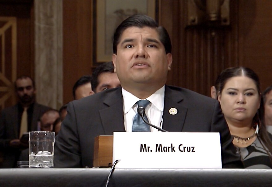 Man at a table with a title card that says Mr. Mark Cruz.