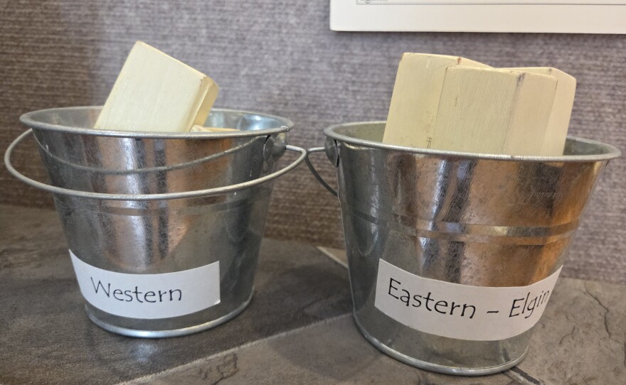 The "Butter Room" display at the Elgin History Museum of a hand crank butter churn which would have been used to make small batches of butter at home, a comparison of the two types of butter sticks known as the "Elgin" and the "Stubby" and a recipe card using Borden's Eagle brand condensed milk and featuring the "Elsie the Cow" mascot