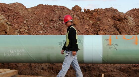 A worker inspects a segment of the Keystone Pipeline before it's lowered into a trench near Stroud, Okla.