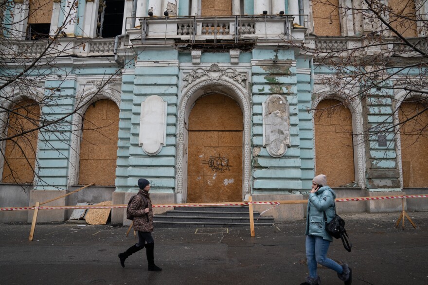 People walk in front of a historic building in Kharkiv that was damaged by a Russian strike.