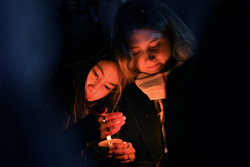 People hold candles during a vigil, Sunday, Dec. 14, 2025, in Providence, R.I., for those injured or killed in the Saturday shooting on the campus of Brown University.