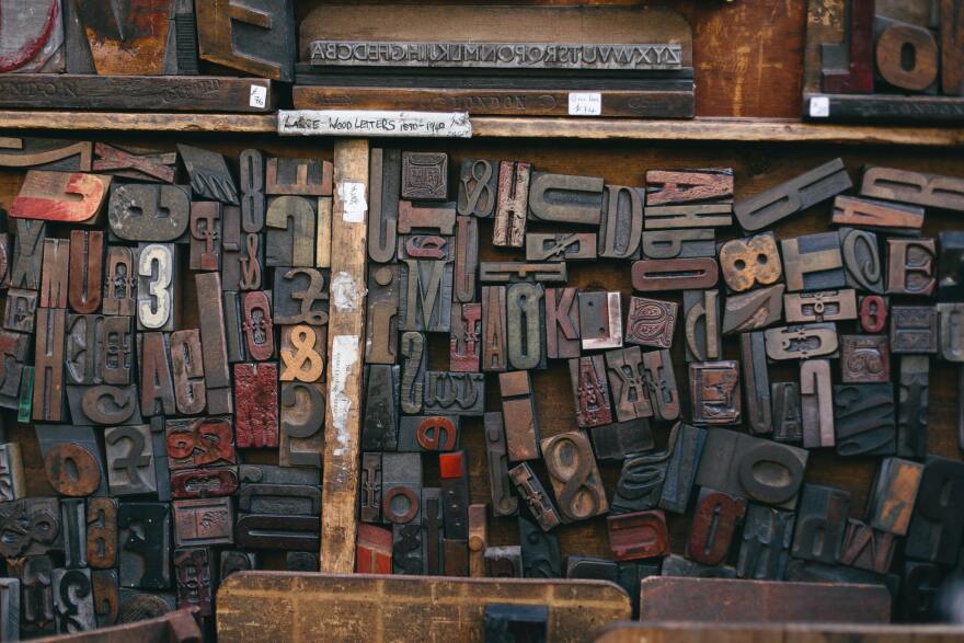 Dozens of rectangular blocks crammed together in what might be a drawer; each block is embedded with a number, letter, or symbol as to be used for press printing