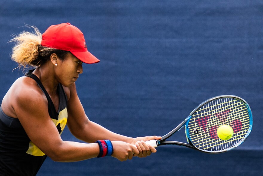 Naomi Osaka hitting a tennis ball with a tennis racket