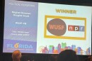 A large screen projects WUSF's logo with the text winner for political reporting Meghan Bowman and Douglas Soule WUSF-FM "Your Florida team covers state politics" 