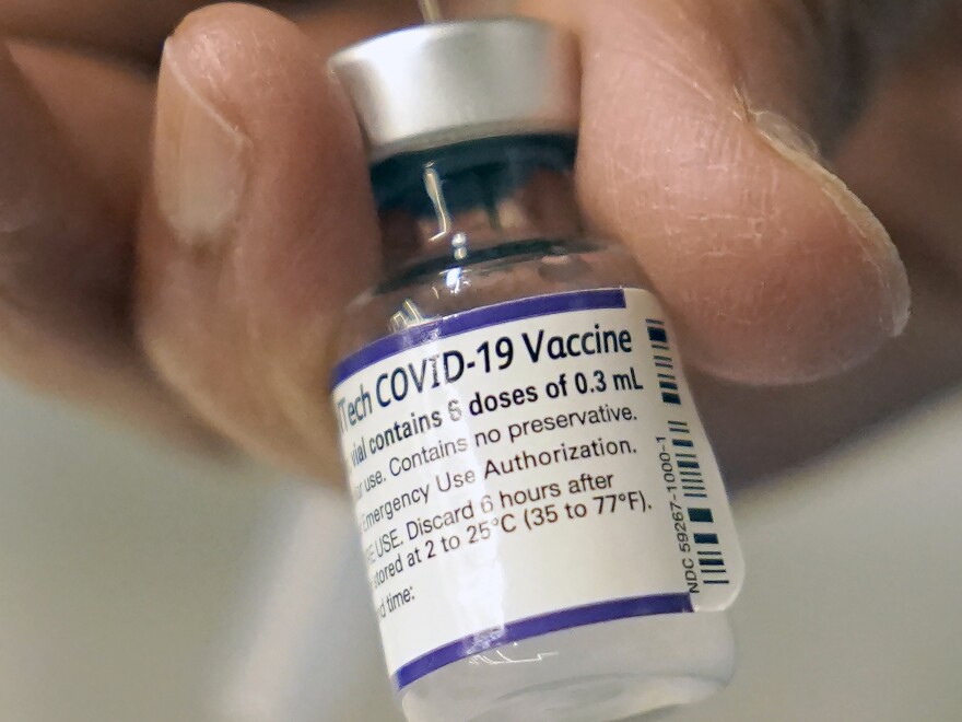 A doctor loads a dose of Pfizer COVID-19 vaccine into a syringe, on Dec. 2, 2021, at a mobile vaccination clinic in Worcester, Mass.