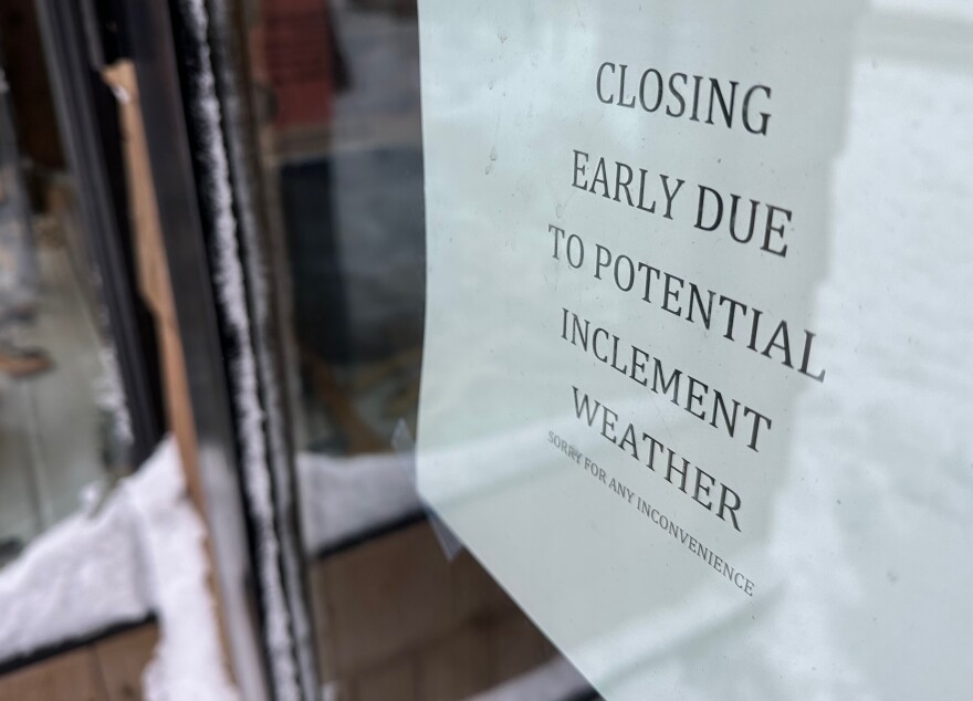 A sign in a storefront window in downtown Traverse City, seen here on Sunday, Jan. 14, notes that they shut off the lights a little early as a winter storm approached heading into the weekend. (Photo: Ed Ronco/IPR News)