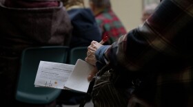 A community member holds an informational sheet on April 5, 2023, during a meeting about community power at city hall in Nashua, N.H. (Raquel C. Zaldívar/New England News Collaborative)