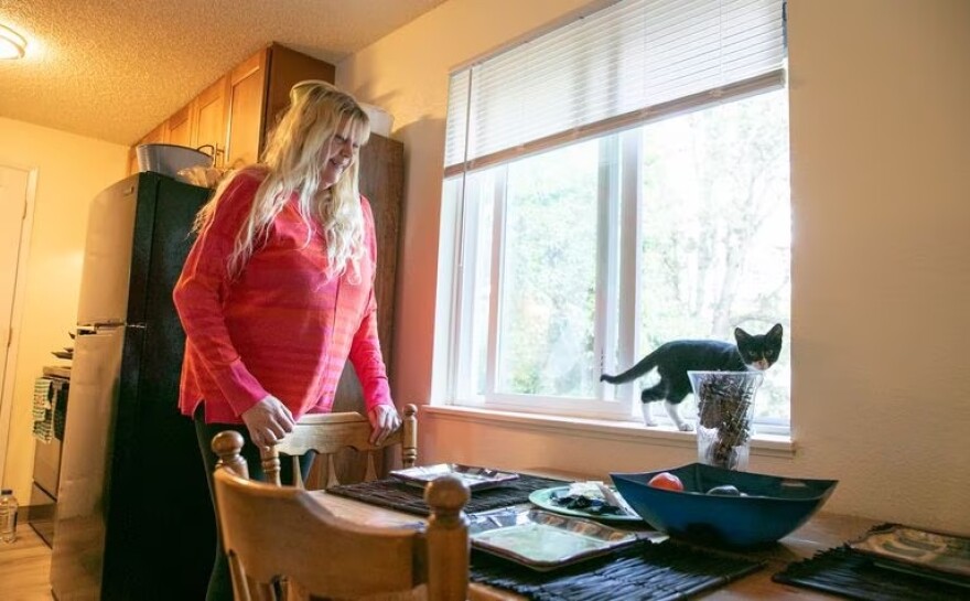 Candi Silvis smiles as her new kitten, Milo, hops on to the windowsill in Beaverton, Ore., on Sept. 1, 2023. After settling into the apartment by herself, Silvis adopted Milo to keep her company and busy in her space.