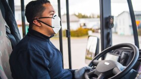 Busdriver with mask puts protecting gloves on his hands to protect himself from the coronavirus epidemic.