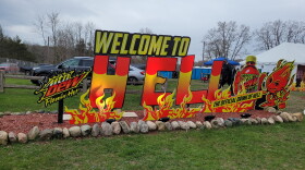 Sign that reads: "Welcome to Hell, Mtn Dew Flamin' Hot, The Official Drink of Hell"with a cartoon of a flame holding a drink bottle.