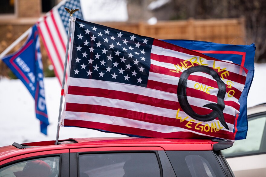A car with a flag endorsing the QAnon conspiracy theory drives by as supporters of President Donald Trump gather for a rally outside the Governor's Residence on Nov. 14 in St. Paul, Minn. [Stephen Maturen / Getty Images]