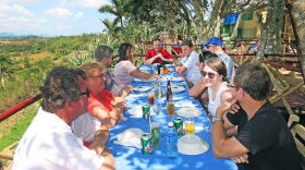 Several people at outdoor table eating a meal in Cuba.  