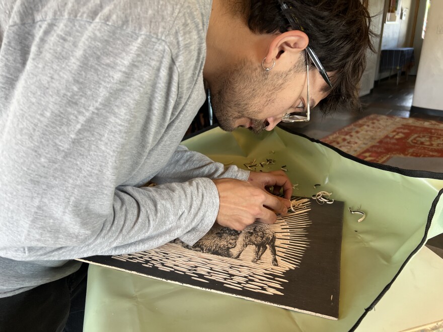Jacob Gutierrez carves a portrait of cows onto a wood block as part of his book, Sacred Herd.
