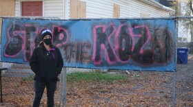 A photo of Tina in front of a sign that reads 'Stop the Kozo.' 
