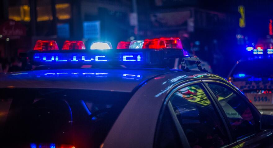 A photo of the top of a police car with the lights on.