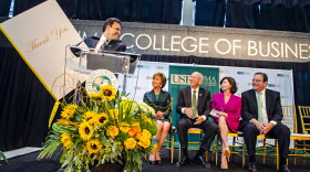 USF Muma College of Business Dean Moez Limayem with a 'thank you' card for Les & Pam Muma, center, at the College renaming ceremony in Oct. 2014. Les Muma will head the search committee for the successor to USF President Judy Genshaft, in green.
