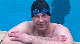 John VanderSloot leaning on the side of a pool in a swim cap