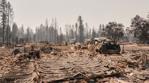 Dozens of houses are seen destroyed in a residential neighborhood as crews begin to check the area after a wildfire hit the northern part of Spokane, Wash., Tuesday, Aug. 4, 2026. (AP Photo/Lindsey Wasson)