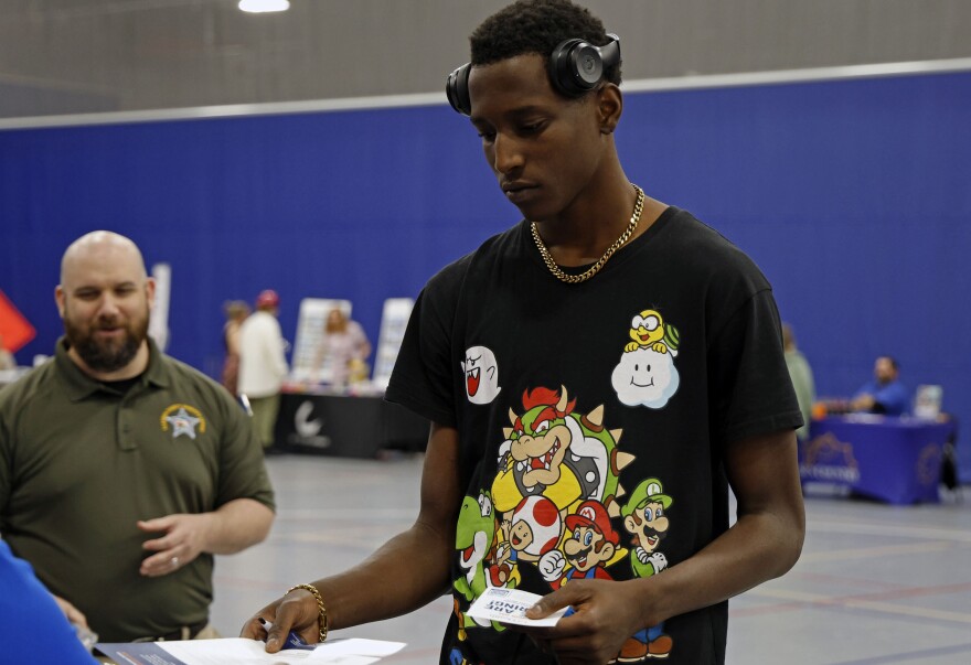 Raheem Roberts, 18, a Newberry High School senior, accepts a pamphlet from an employer during the Seniors Without a Plan Job Fair at the Alachua County Sports and Events Center on Thursday, April 25, 2024.