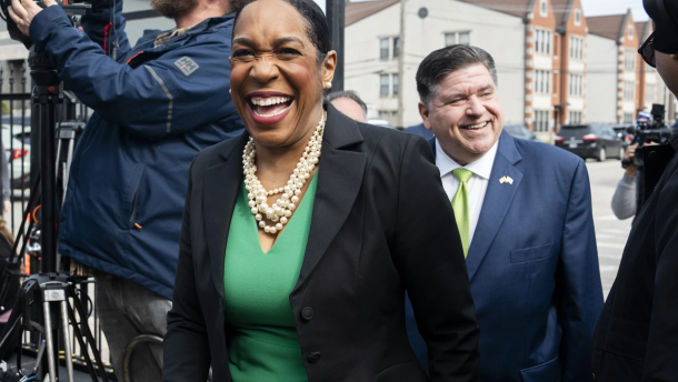 Juliana Stratton, wearing a green dress and black blazer, walks in front of Gov. JB Pritzker. Pritzker is endorsing Lt. Gov. Juliana Stratton’s bid for the U.S. Senate on April 25, 2025.